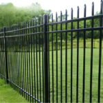 Custom black steel fence surrounding a well-maintained lawn, demonstrating elegance and durability.