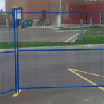 Blue temporary fence panels securing a construction site parking area.