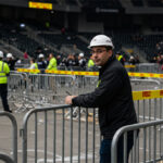 Workers setting up crowd control barricades at a large event venue, demonstrating the practical use of barriers in managing crowd flow.