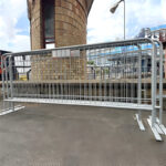 A crowd control barrier positioned in an urban area, showcasing its structure near a building with a modern design.