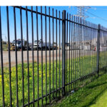 Black metal fence providing security around a commercial property.