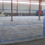 Installed blue temporary fence in an industrial setting, demonstrating its application for site security and crowd control.