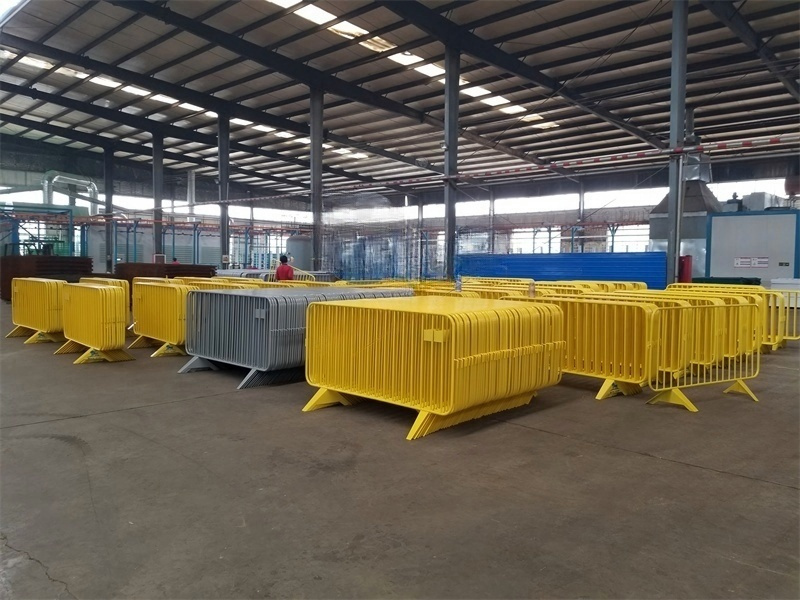 A warehouse with neatly stacked yellow, blue, and gray crowd control barriers, ready for distribution or deployment.