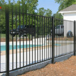 Black aluminum pool fence surrounding a swimming pool area, providing safety and aesthetic appeal.