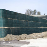 A large, multi-layered defensive barrier wall constructed with wire mesh units filled with soil, used as a protective structure.