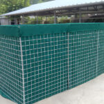 A fully assembled wire mesh barrier with a green fabric lining, set up outdoors on a concrete surface.