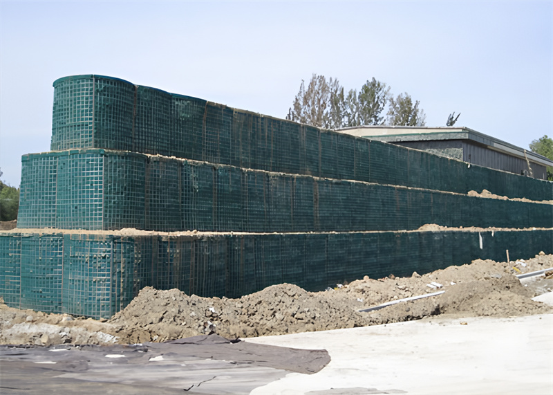 A large, multi-layered defensive barrier wall constructed with wire mesh units filled with soil, used as a protective structure.