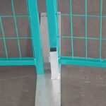 A close-up view of a metal post on a temporary fence, illustrating the base where the fence panel is secured. The surface is concrete, and the area is clean and well-maintained.