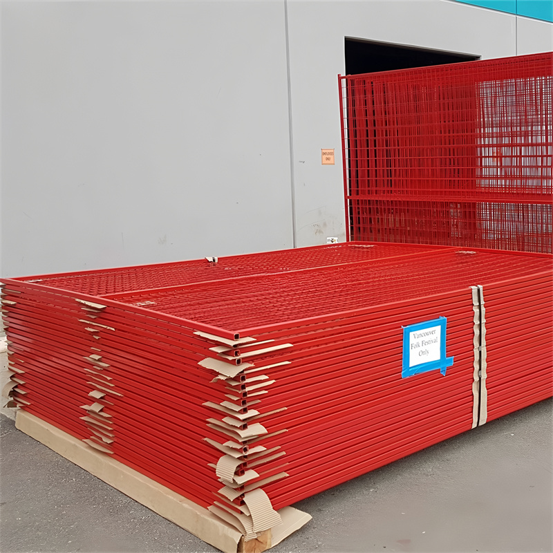 A stack of red wire mesh fence panels arranged neatly on a pallet. The panels are labeled for a specific event, indicating they are for temporary use.