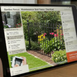 A tablet displaying a digital checklist for garden fence maintenance. The screen shows an image of a black metal fence surrounded by flowers, with various maintenance tips listed, such as routine cleaning and rust prevention.
