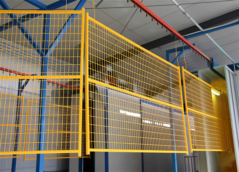 A series of yellow wire mesh panels suspended from a blue structure in a warehouse setting, designed for safety or security purposes.