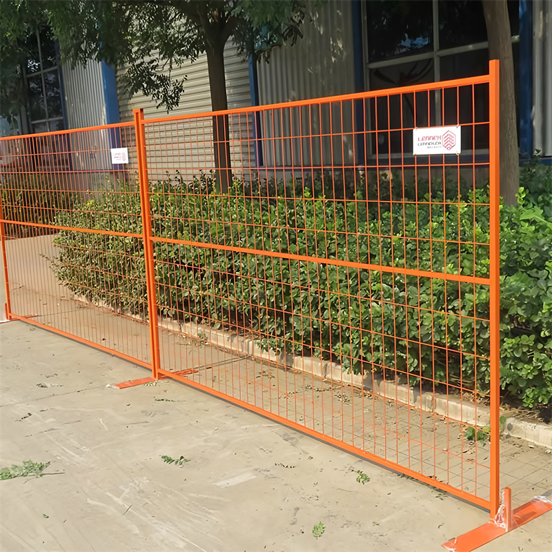 An orange metal fence displayed outdoors, surrounded by green bushes.