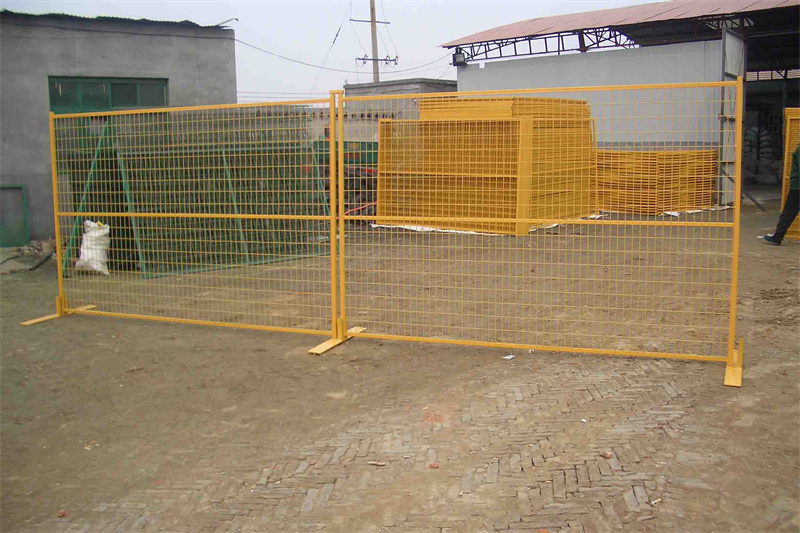 A section of bright yellow temporary fencing is displayed, showing its grid design. The fence is secured with concrete bases on a dirt surface, indicating its use for crowd control or construction sites.