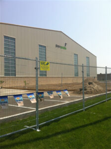 A construction site fence surrounding a building with the sign "Players Paradise" on the wall. The fence has a "VRE Installers Secure Fence Solutions" sign and colorful banners along its length.