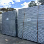 Two large, shrink-wrapped stacks of temporary fencing panels, each labeled "125PCS," prepared for bulk delivery to Australia.