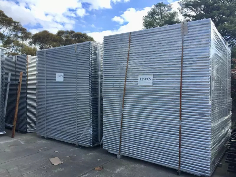 Two large, shrink-wrapped stacks of temporary fencing panels, each labeled "125PCS," prepared for bulk delivery to Australia.