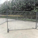 Gray temporary fence panels with wheels and flat stands forming an enclosure in an outdoor setting.