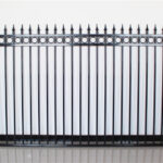 A single, high-quality black steel fence panel with spear-point finials and decorative rings, displayed against a plain white wall to showcase its design.