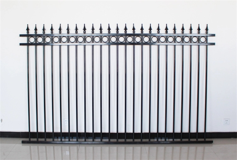 A single, high-quality black steel fence panel with spear-point finials and decorative rings, displayed against a plain white wall to showcase its design.