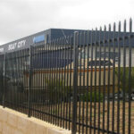 A black steel picket fence with spear tops providing security for a commercial property after being successfully imported and installed.