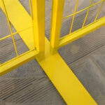Close-up view of a yellow temporary fence panel's robust base and welded frame connection, highlighting its construction.