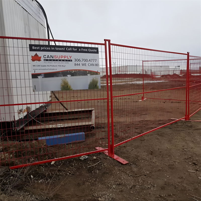 Red temporary welded wire mesh fence with flat base feet, securing a dirt construction site. A CANSUPPLY wholesale sign is attached to the fence.