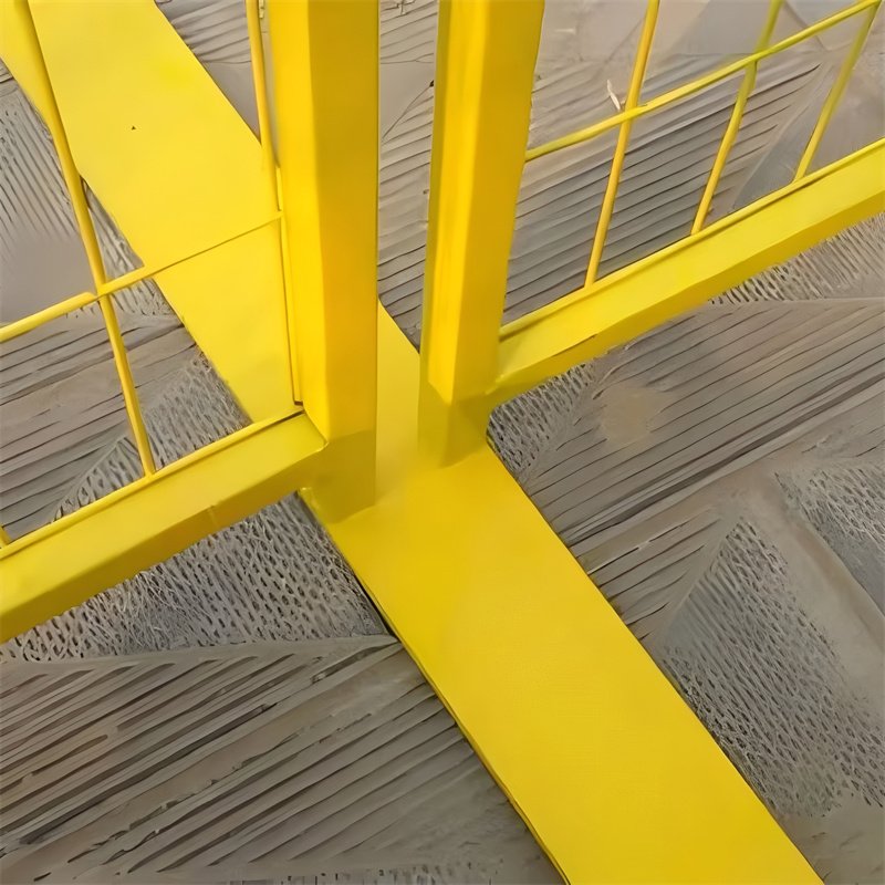 Close-up view of a yellow temporary fence panel's robust base and welded frame connection, highlighting its construction.