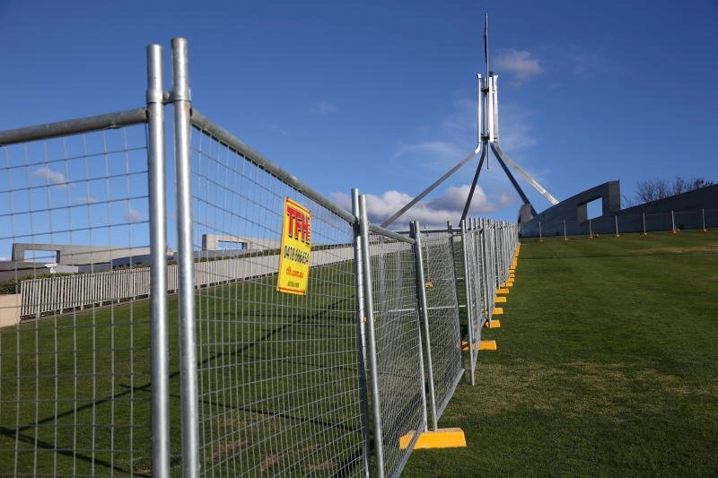 DB Fencing's galvanized temporary mesh fence with yellow plastic feet installed on a sloped grassy site, showcasing compliance with Australian standards and suitability for construction and event management clients.