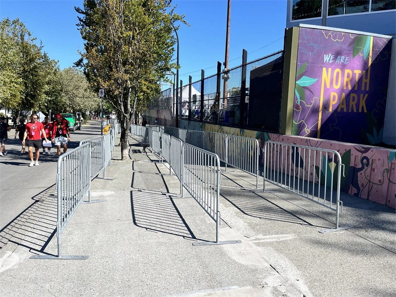 DB Fencing portable metal crowd control barriers installed along a city sidewalk for event crowd management, showcasing durable hot-dipped galvanized construction designed for public gatherings and construction site security.