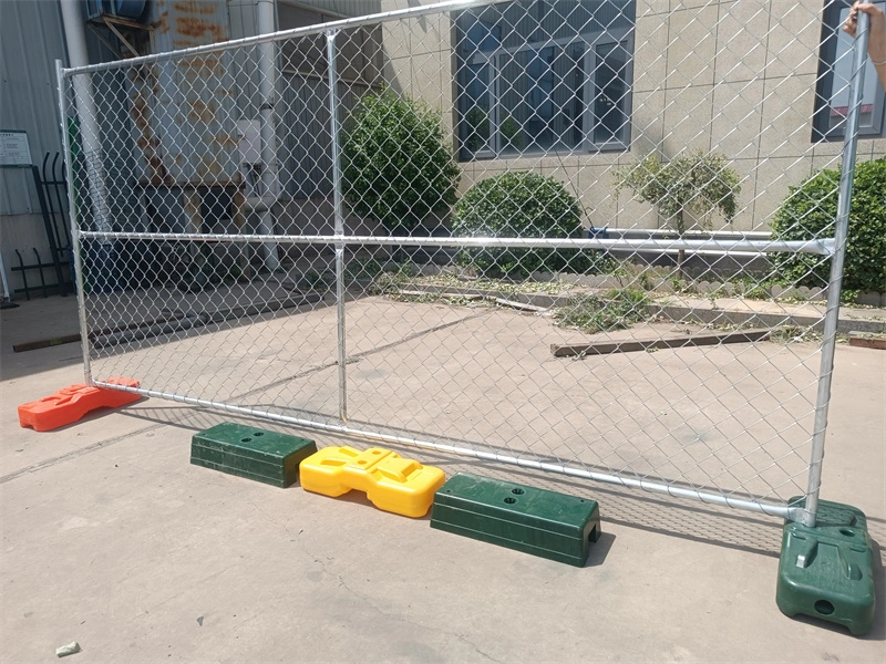 Temporary chain-link fence with galvanized metal mesh and custom-colored plastic feet (orange, yellow, green) from DB Fencing, a leading wire mesh manufacturer, demonstrating our in-house plastic feet manufacturing and OEM customization for construction and event applications.