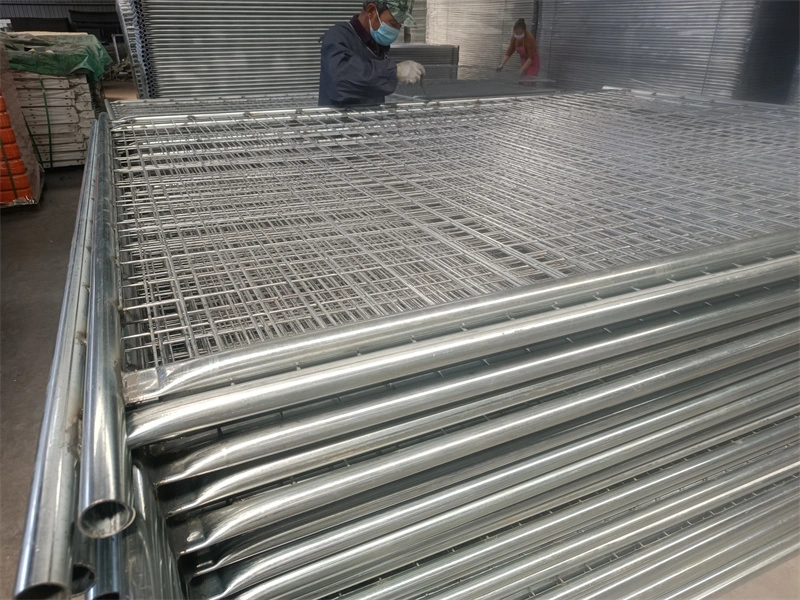 DB Fencing's galvanized temporary fence wire mesh panels and metal posts in a manufacturing facility, showcasing our ISO9001-certified production and hot-dipped galvanized finishes for durable outdoor use.