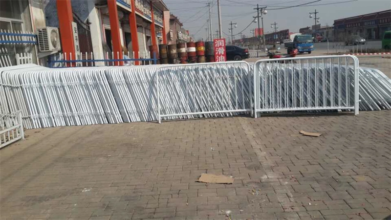 Stack of white galvanized crowd control barriers manufactured by DB Fencing, a leading wire mesh fence exporter, displayed in their factory yard for distribution to construction firms and event management companies.