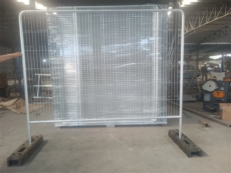 A galvanized metal temporary fence panel with a grid mesh, supported by custom black plastic feet, displayed in DB Fencing's factoryshowcasing their durable, AS 4687-compliant temporary fencing solutions for construction, events, and agricultural use.