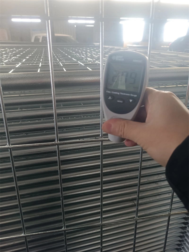 A hand operates a digital thickness gauge to measure the hot-dipped galvanized coating on DB Fencing's temporary wire mesh fence, demonstrating compliance with durability standards for harsh outdoor environments and quality assurance in manufacturing.