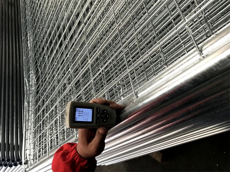 A worker uses a coating thickness gauge to measure the hot-dipped galvanized finish on a temporary fence component, demonstrating DB Fencing's quality control and compliance with durability standards for harsh outdoor environments.
