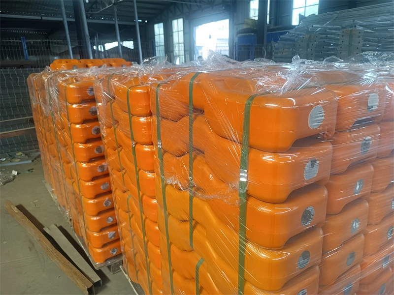 Stacks of orange plastic temporary fence feet wrapped in plastic and secured on pallets, representing DB Fencing's bulk packaging for B2B clients like construction firms and event management companies.