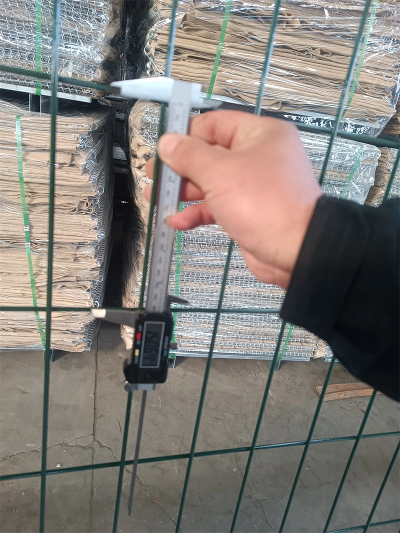 A hand uses a digital caliper to measure the wire thickness of a green temporary fence panel, showcasing DB Fencing's rigorous quality control process for AS 4687-2022 compliant wire mesh products.
