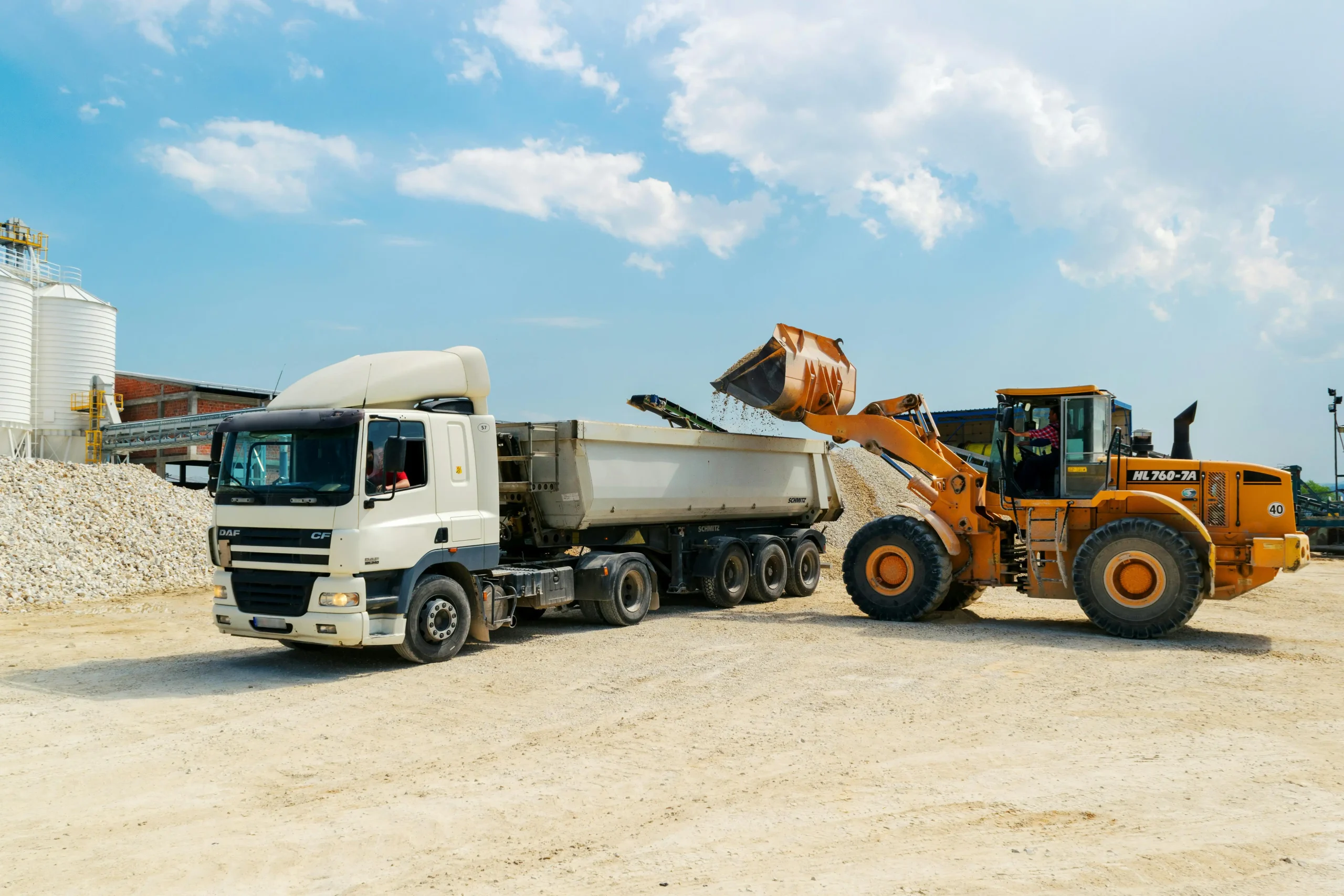 excavator dumping rubble into Hesco barrier