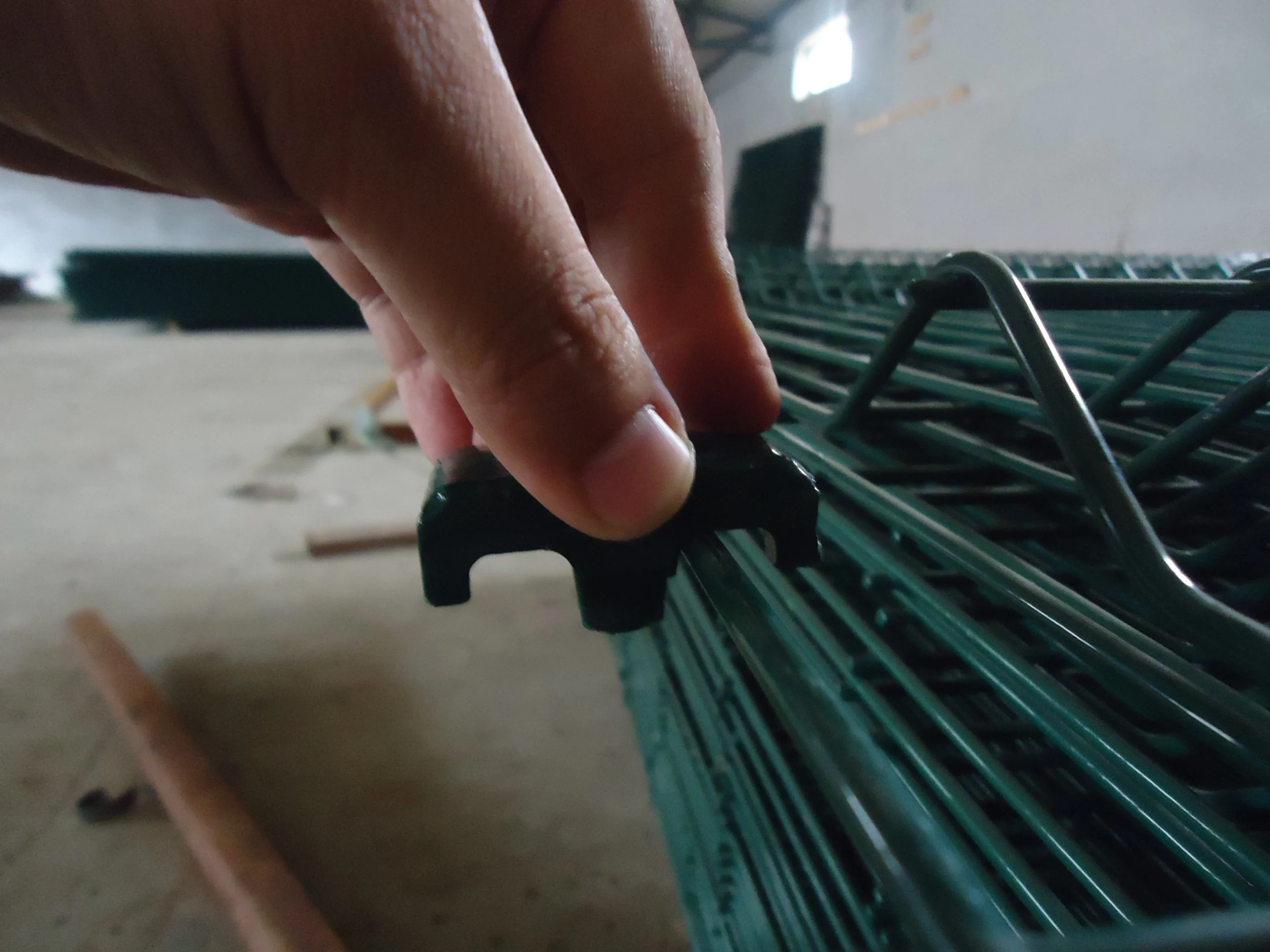Anping Deban Metal Wire Mesh Products Co., Ltd. showcases the installation of a plastic foot onto a green powder-coated anti-climb wire mesh fence panel. This component provides a stable, non-marking foundation for temporary security fencing systems on construction sites.