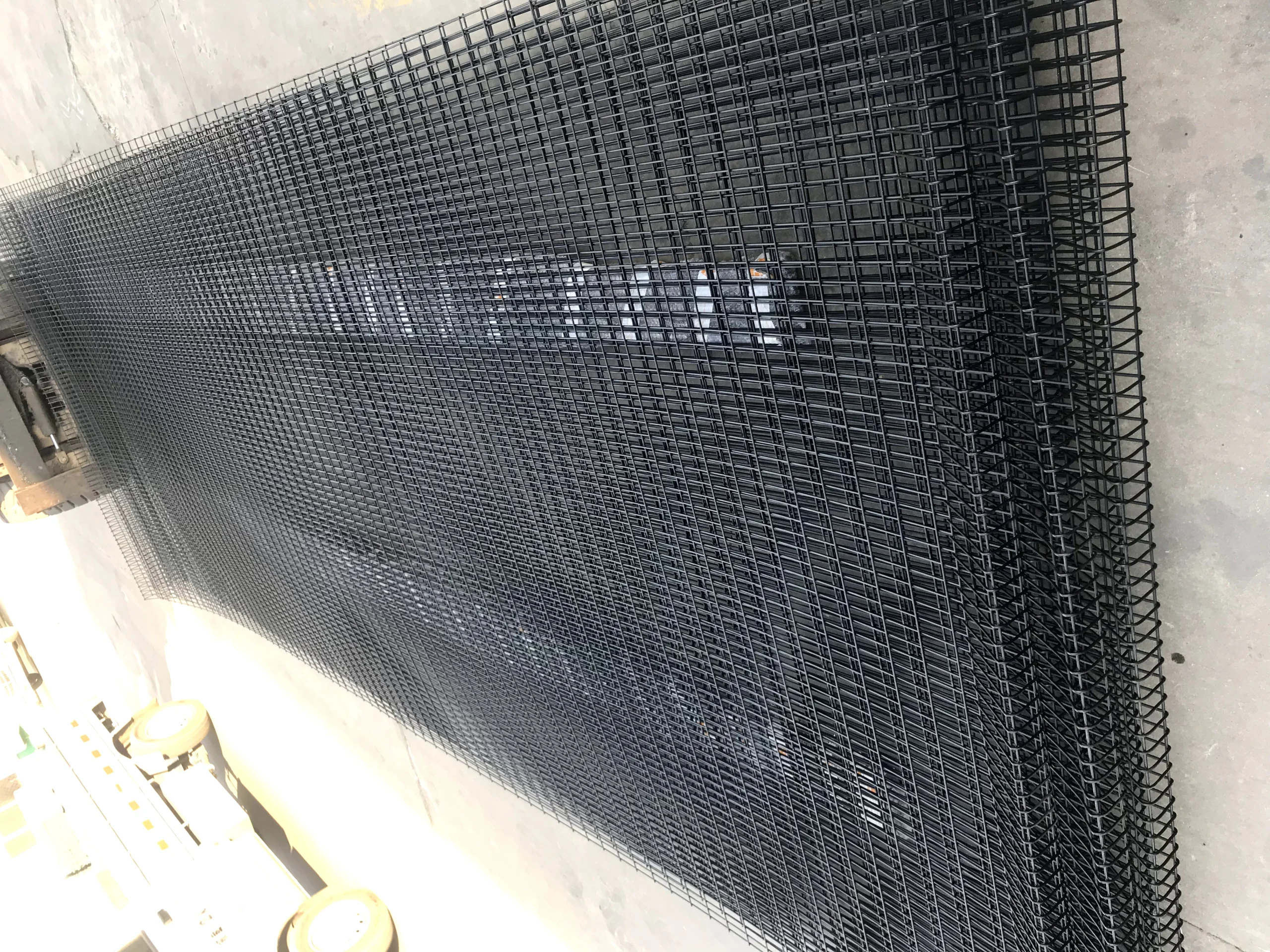 A large, neatly stacked quantity of black powder-coated welded BRC fence panels, showcasing DB Fencing's robust production capacity for bulk orders. These high-quality wire mesh fencing panels are manufactured to provide secure and durable perimeter solutions, meeting the demands of construction firms and global distributors.