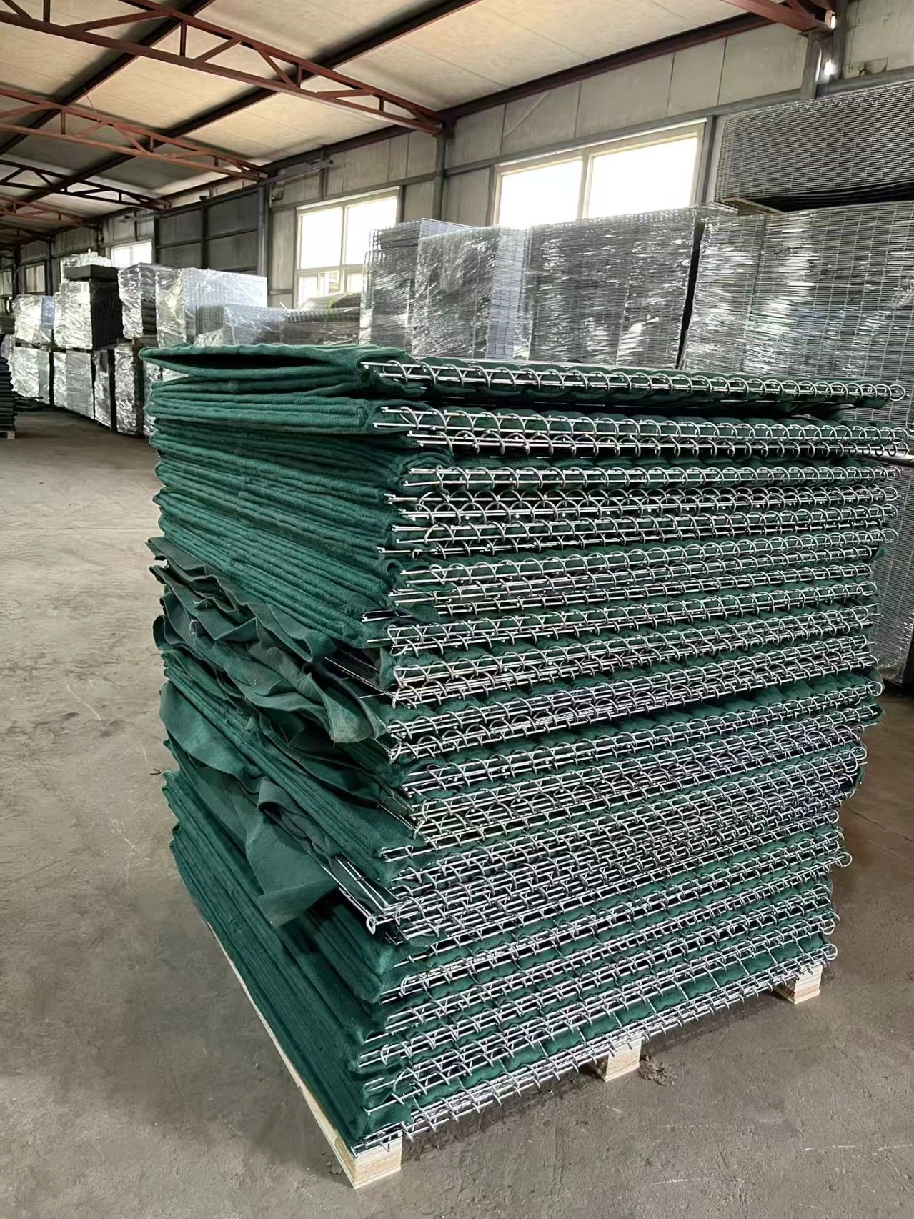 Palletized stack of high-strength Hesco barriers featuring hot-dipped galvanized wire mesh and durable green textile lining. Produced by DB Fencing, these temporary fencing units are built for Australian compliance and construction site security.