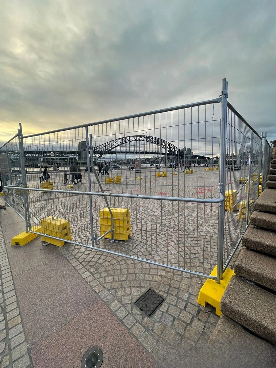 A view of robust DB Fencing temporary fencing systems for construction sites in Sydney, Australia, featuring our durable galvanized wire mesh panels secured by bright yellow plastic feet. This setup demonstrates our high-quality barriers for public areas, meeting Australian standards for site security and crowd control.