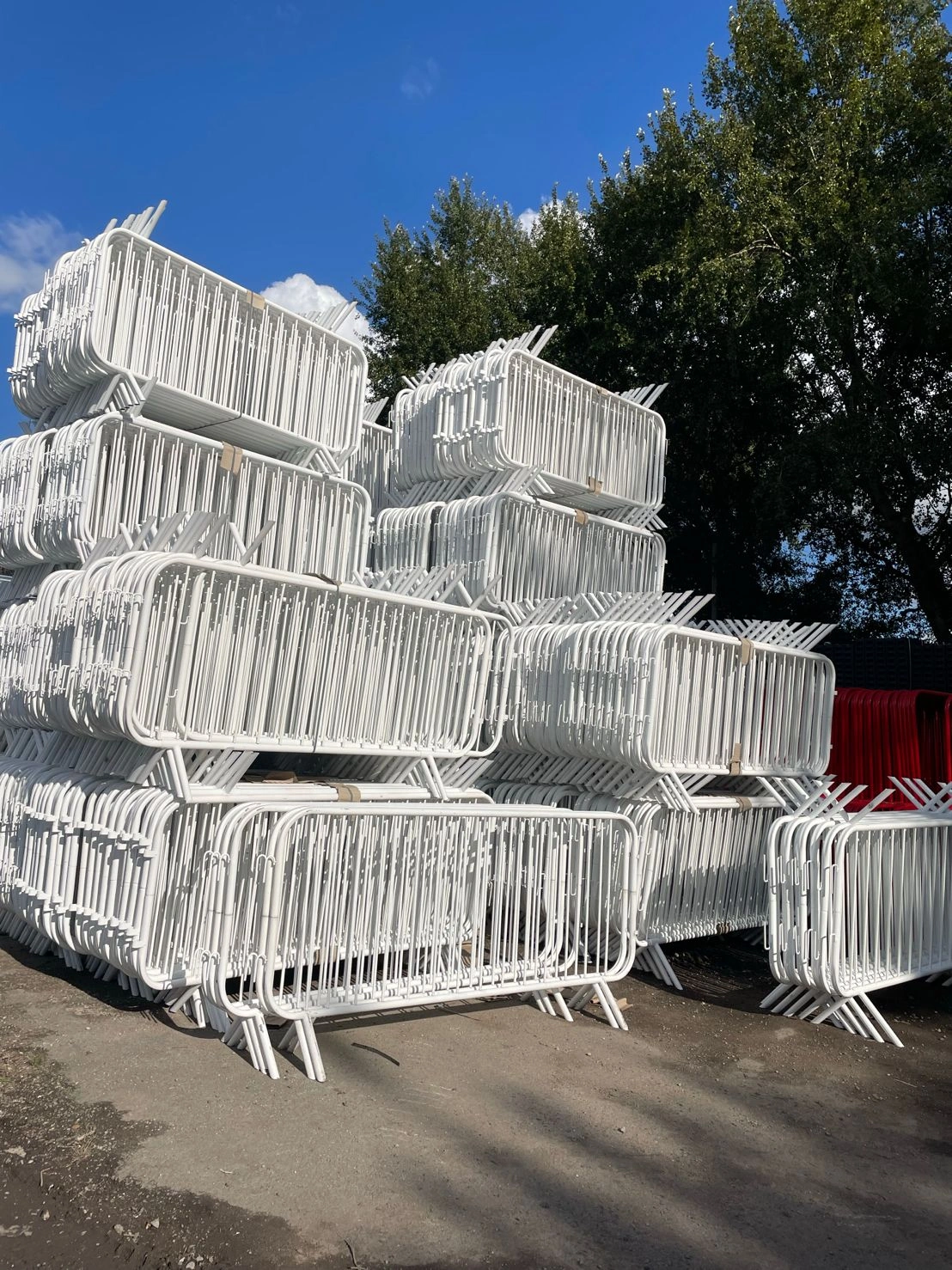 A large, neatly stacked inventory of pristine white steel Crowd Control Barriers for Events & Public Safety, showcasing DB Fencing's manufacturing readiness for bulk export. These durable, hot-dipped galvanized barriers are ideal for event management companies and distributors seeking high-quality, compliant crowd management solutions.