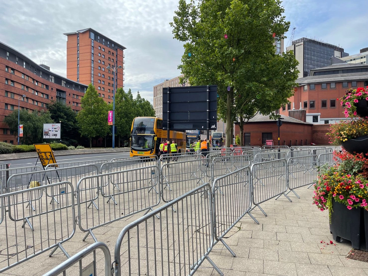 An urban street scene featuring DB Fencing's robust crowd control barriers for events and public safety, directing pedestrian flow near a double-decker bus and event staff. These hot-dipped galvanized barriers, compliant with AS 4687-2022, are designed for durability and ideal for event management companies and public safety applications.
