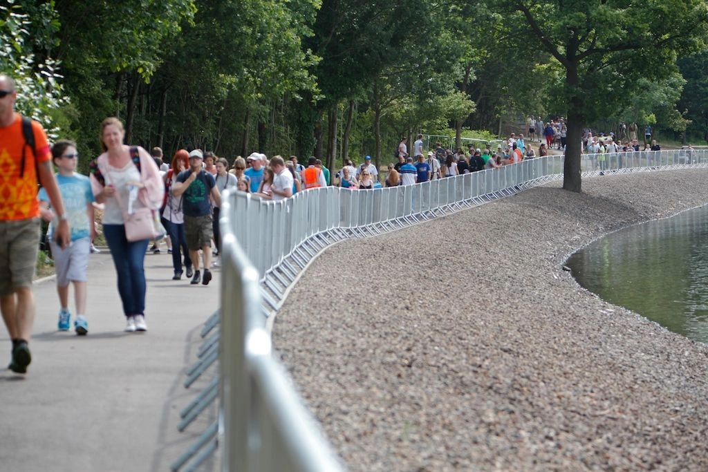 DB Fencing's hot-dipped galvanized crowd control barriers effectively manage pedestrian flow along a scenic waterfront path during a public gathering or event. These robust metal barriers, compliant with international standards, are crucial for event management companies needing reliable perimeter management and public safety solutions for large crowds.