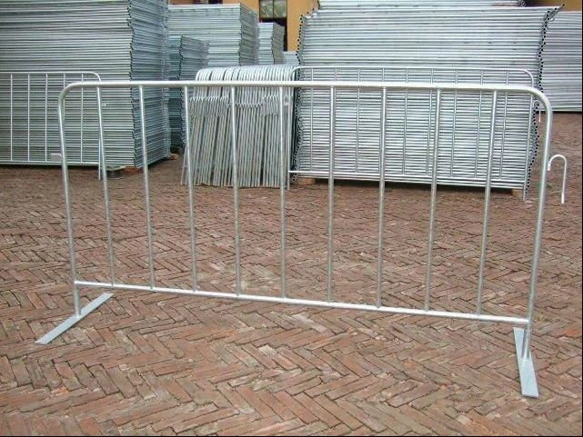A durable hot-dipped galvanized steel crowd control barrier, manufactured by DB Fencing, stands ready for deployment. The background reveals extensive stacks of these high-quality barriers, demonstrating our capacity as a leading B2B supplier for event management companies and global distributors.
