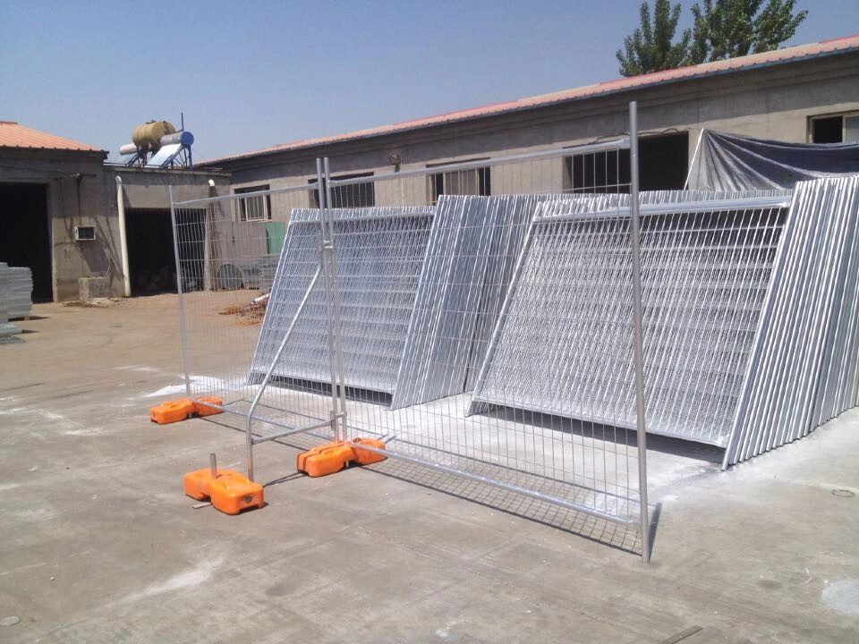 A large stock of DB Fencing's galvanized temporary fencing systems, featuring robust wire mesh panels and distinctive orange plastic feet, stored in an outdoor manufacturing yard. These high-quality temporary fence panels are ideal for construction site security and event perimeter management, reflecting DB Fencing's compliance with Australian standards and export capabilities.