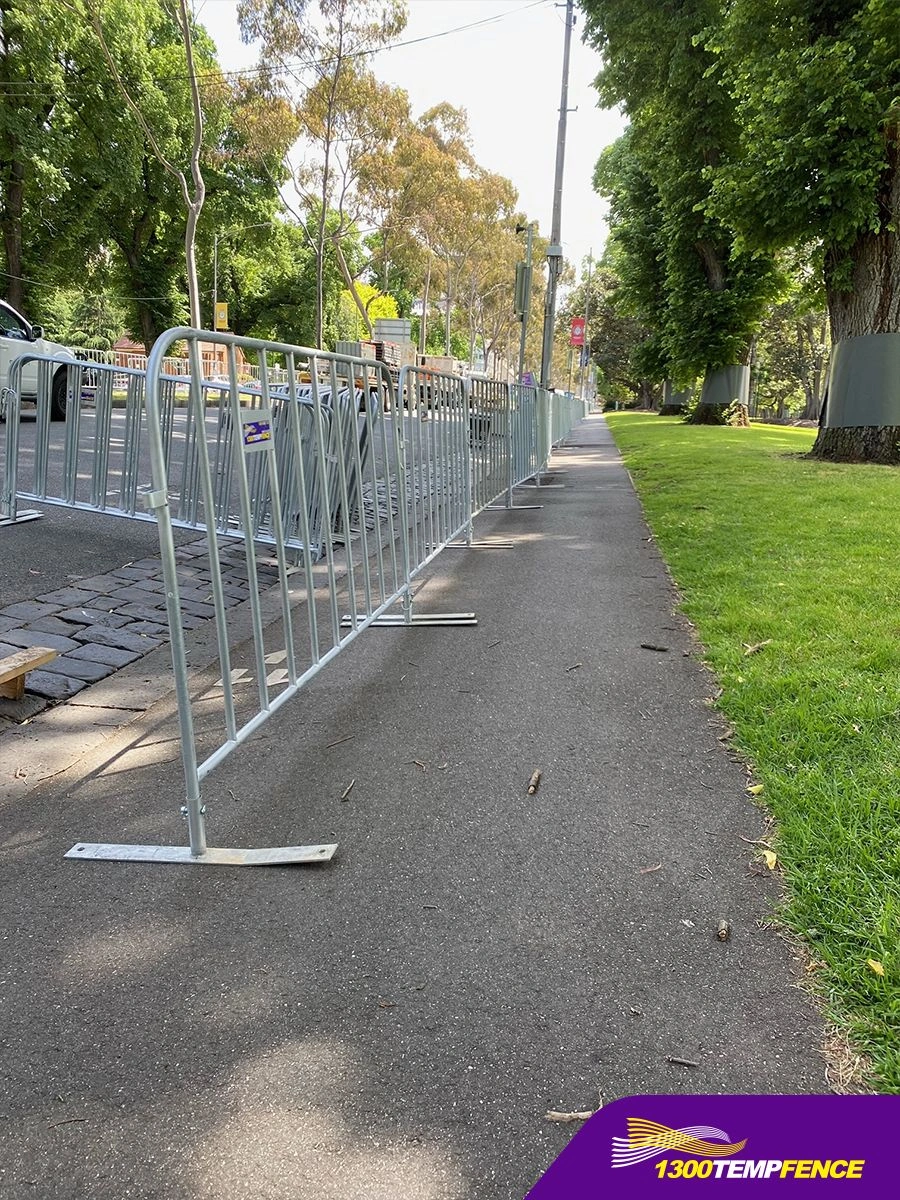 A long line of DB Fencing hot-dipped galvanized crowd control barriers extends along a paved sidewalk, effectively managing event perimeter safety for public gatherings. These durable, AS 4687-compliant crowd control barriers are manufactured in Anping and designed for harsh outdoor environments.