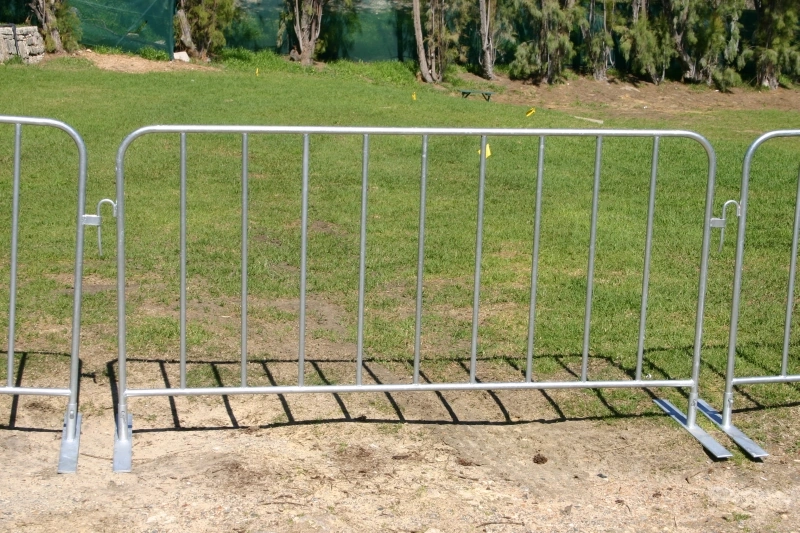Robust hot-dipped galvanized steel crowd control barriers from DB Fencing, featuring interlocking hooks and stable flat bases, are shown set up for effective event perimeter management and public safety. These durable barriers, compliant with Australian Standard AS 4687-2022/2007, are ideal temporary fencing solutions for event management companies and public gatherings in harsh outdoor environments.