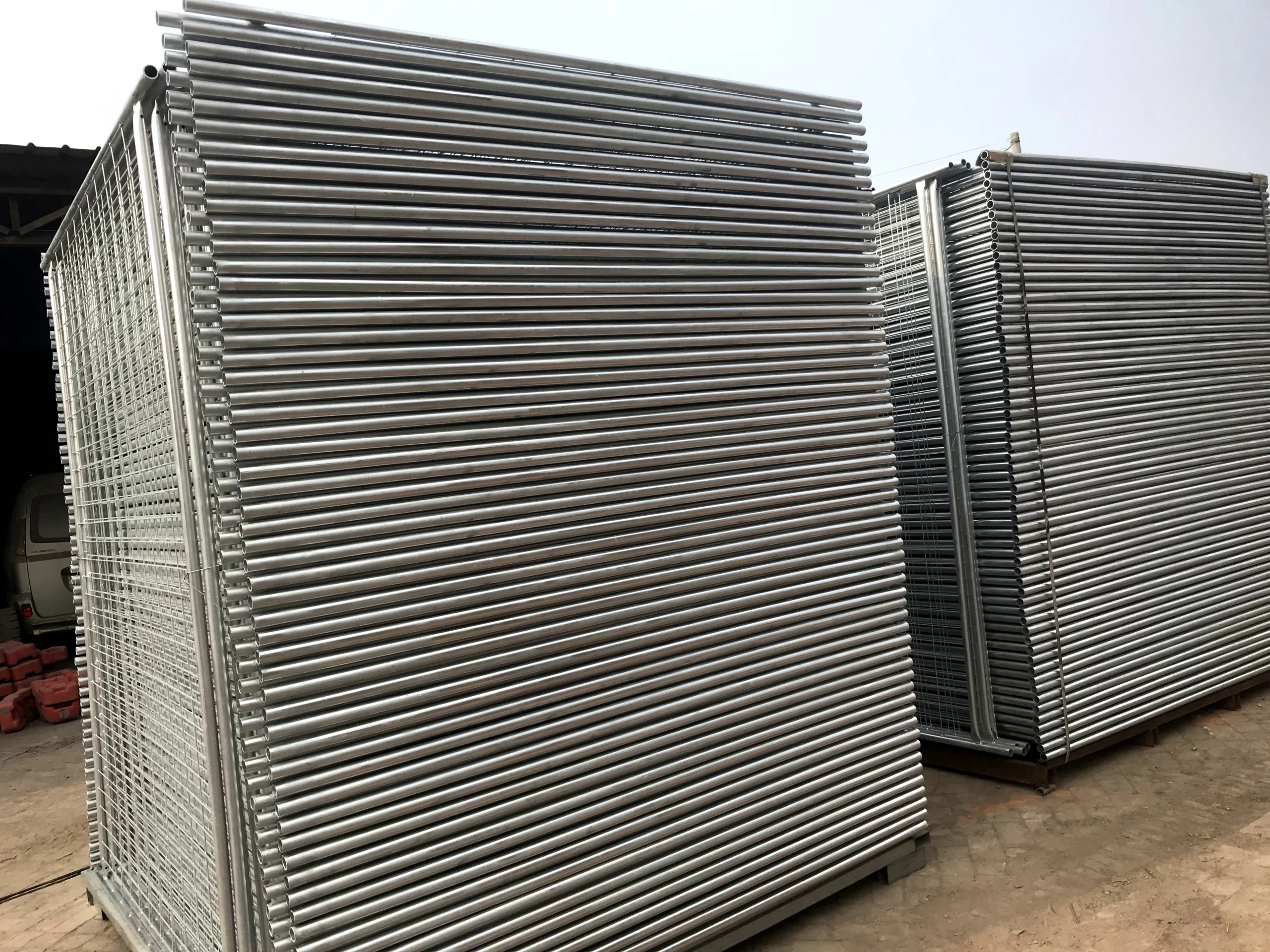 Large, neat stacks of DB Fencing's hot-dipped galvanized temporary fencing systems for construction sites, featuring tubular frames and welded mesh infills. These durable panels highlight our bulk production capacity as a leading 'one-stop' wire mesh fence manufacturer, ready for export to Australia, New Zealand, and global markets.